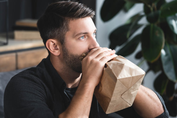 Man breathing into a paper bag - deposit photos