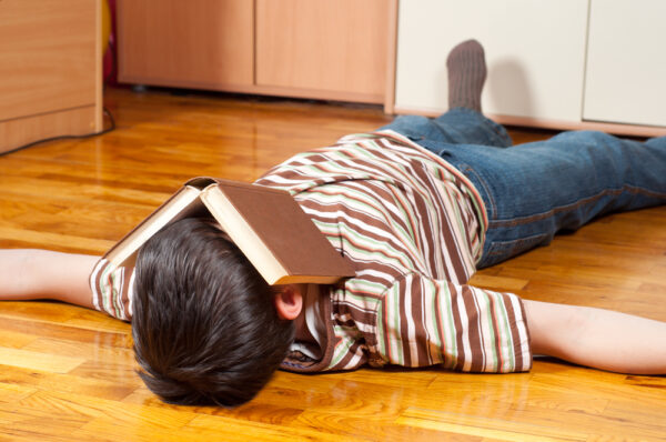 Coming Down - teen on floor with book on his face - deposit photos