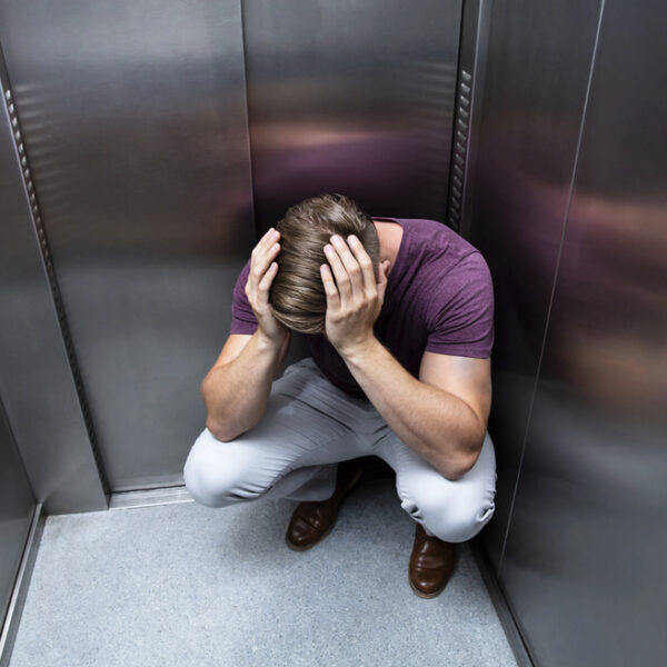man croucing in corner - deposit photos