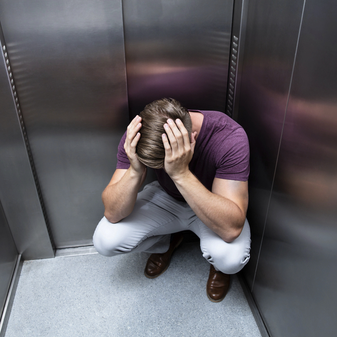 man croucing in corner - deposit photos